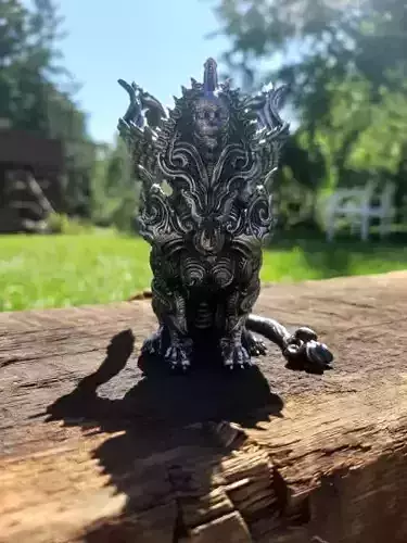 Sphinx silver demon figurine on piece of wood